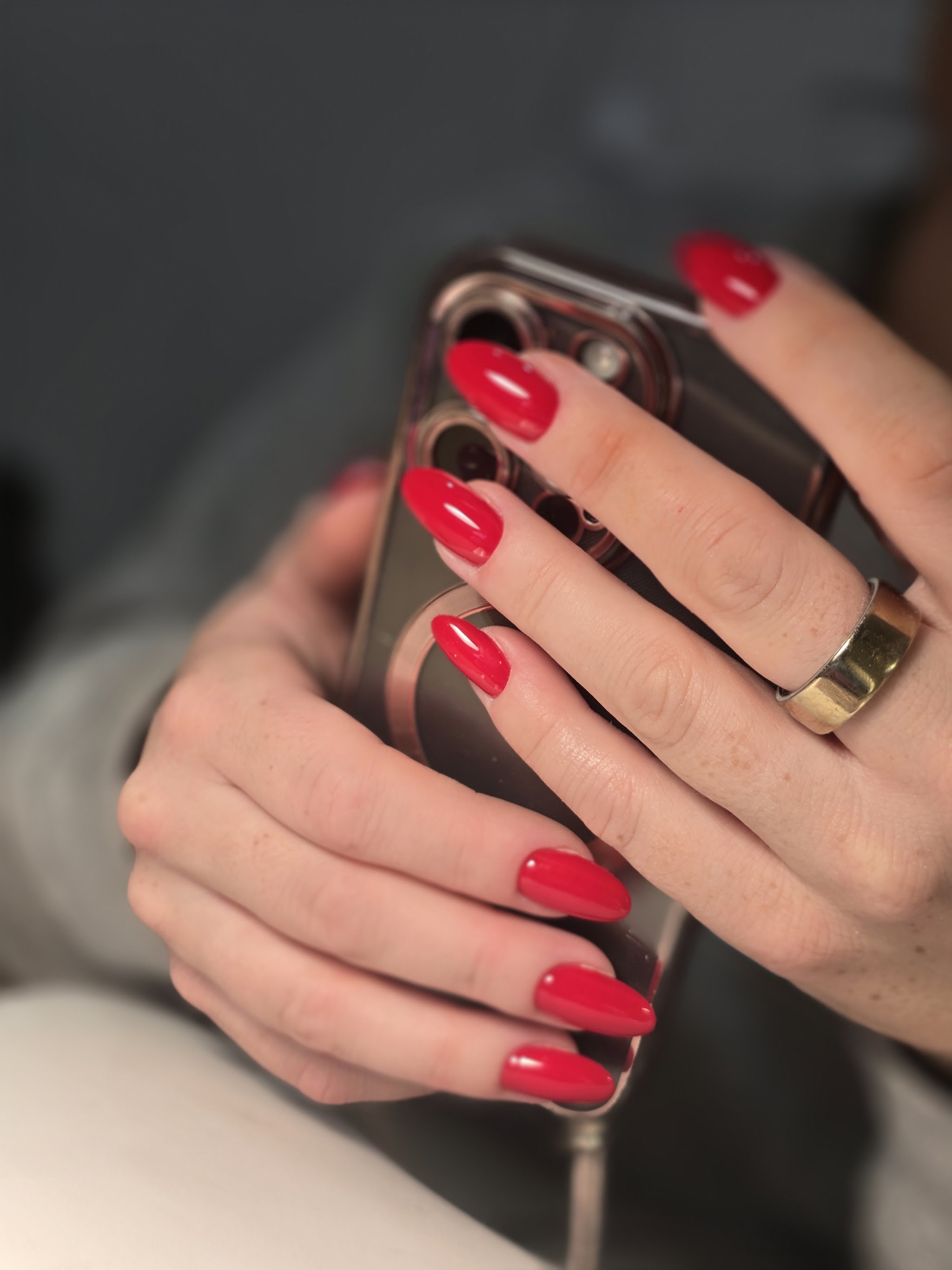 Handen met glanzend rode nagels rond een telefoon
