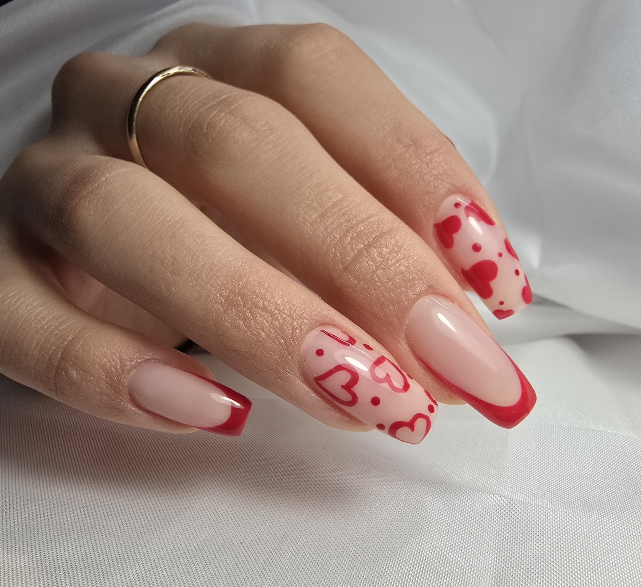 Nude nagels met een rode French en rode hartjes als nail art
