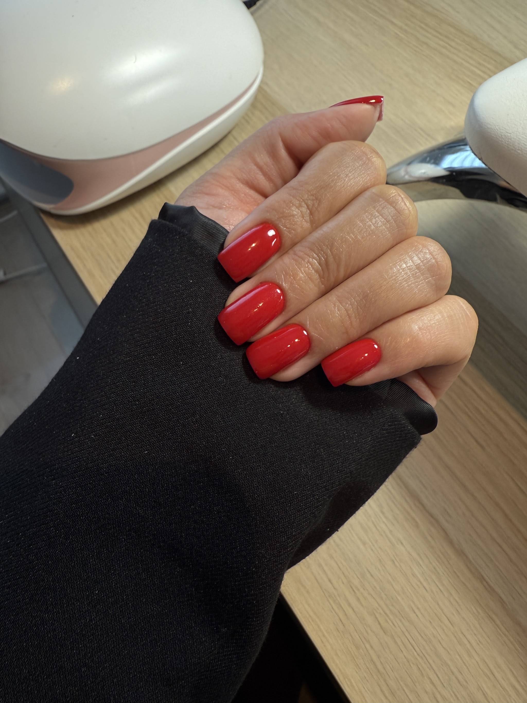 Rode nagels aan de werktafel in de studio, naast de nagellamp
